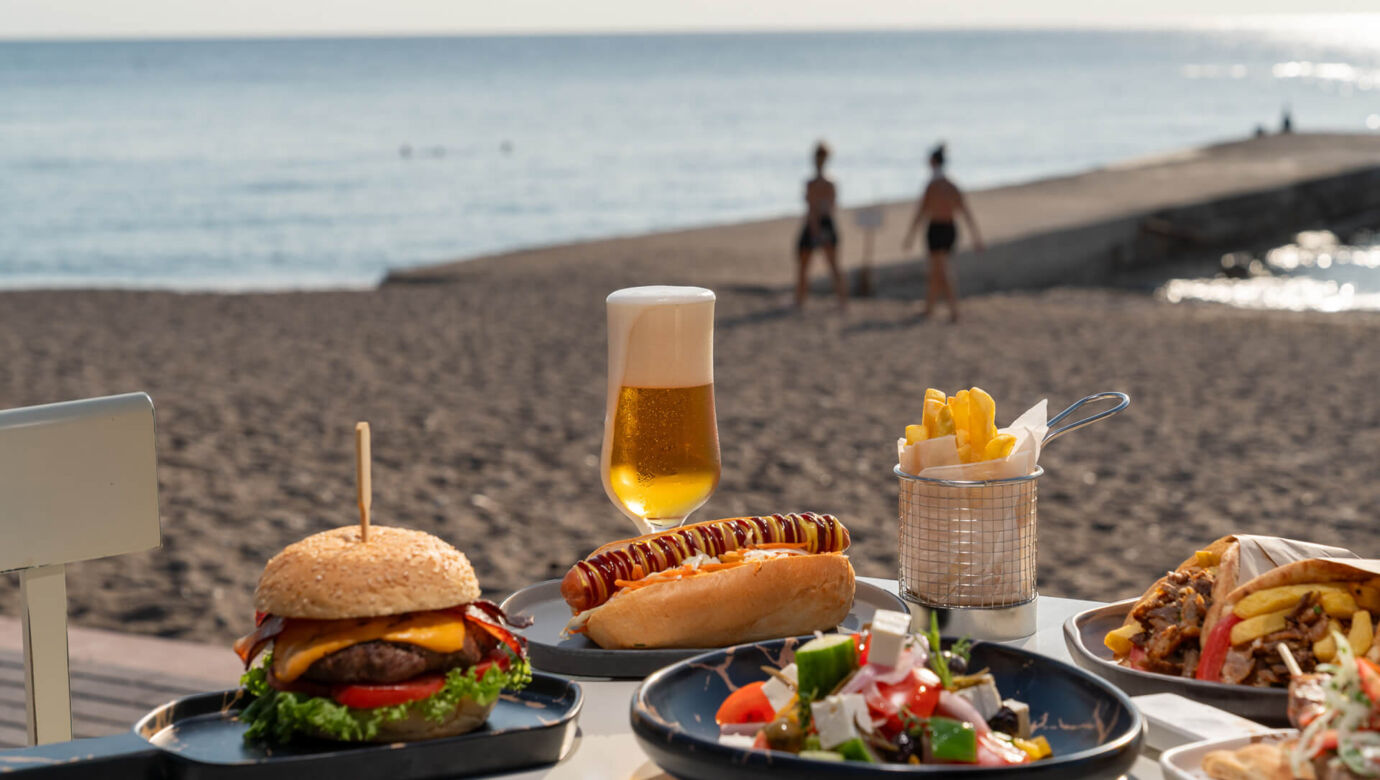 Table full of casual food and a glass of beed at Amada Colossos Resort