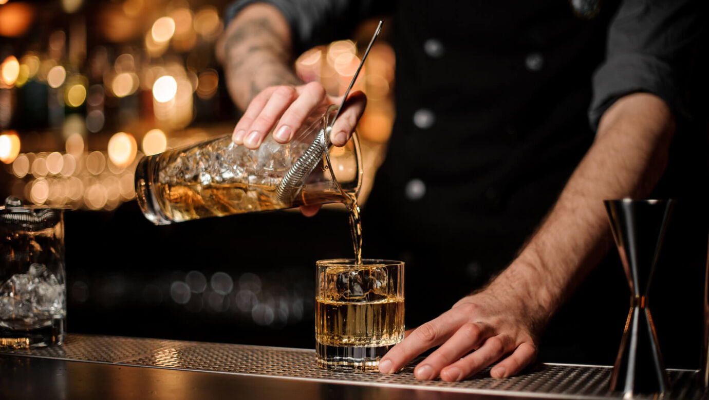 Barman pouring drink at Amada Colossos bar