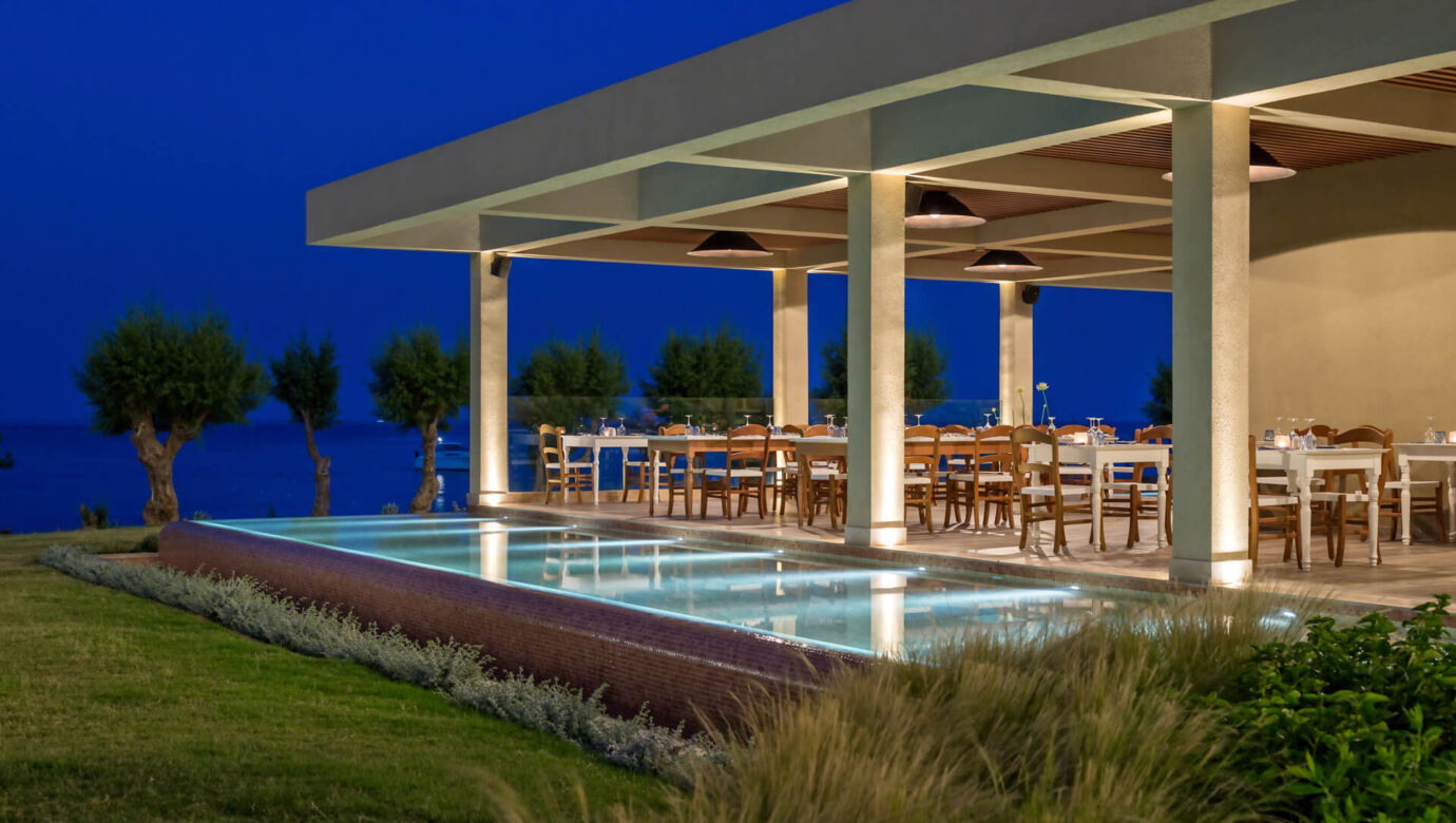 Outside tables at a resturant with garden and sea view at Amada Colossos Resort