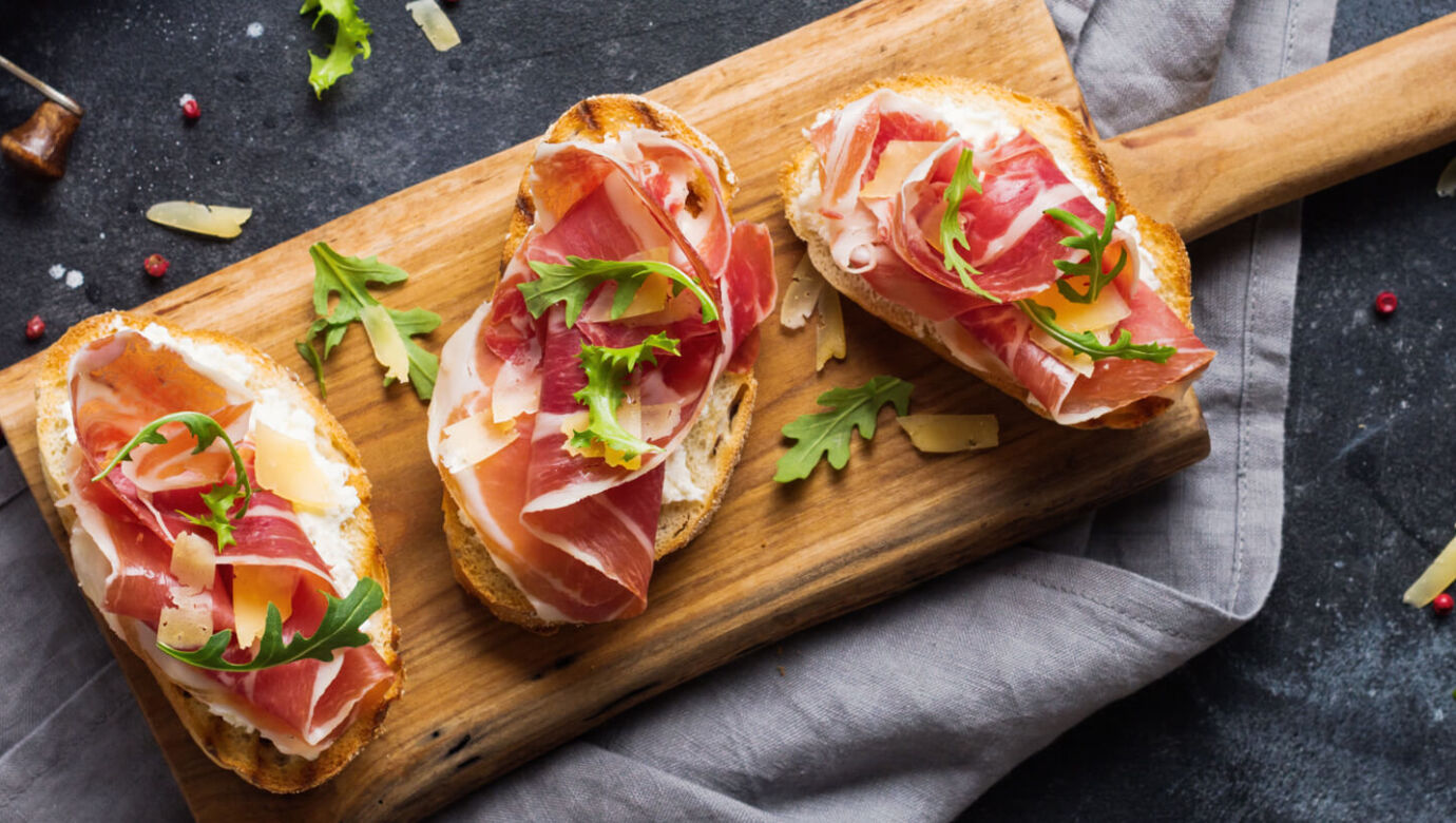 Bread with prosciutto on a wooden platter