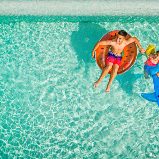Two kids playing with inflatable toys at Amada Colossos Resort pool