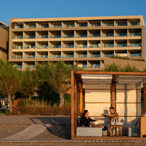 Couple enjoying wine in beach sunbeds with wooden frames at Amada Colossos