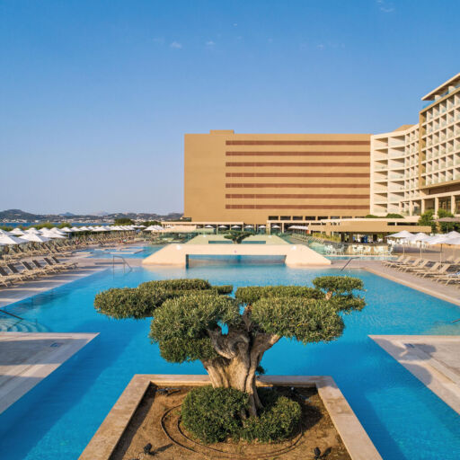View of the pool with sunbeds and at the background the Amada Colossos Complex