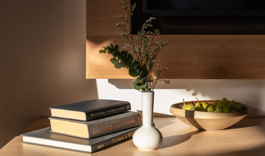 Side table with books , plants and a bowl with fruits