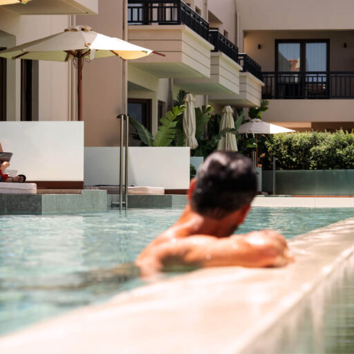 Man in Swim up pool watching a woman reading a magazine at Asterion Suites