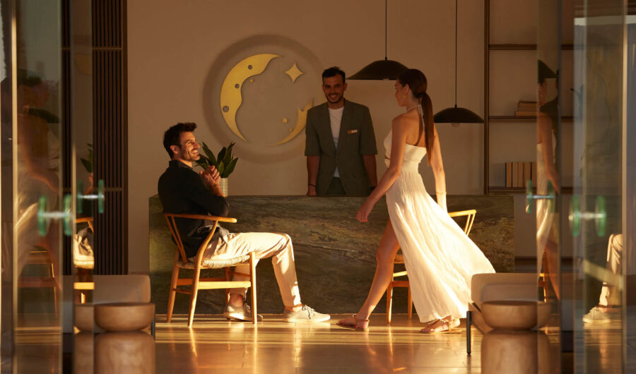 Woman walking torward a man in front of reception of Asterion Suites
