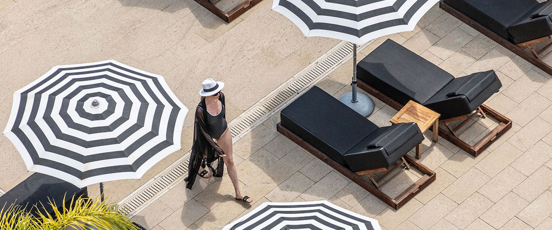 Woman walking by luxury hotel pool loungers