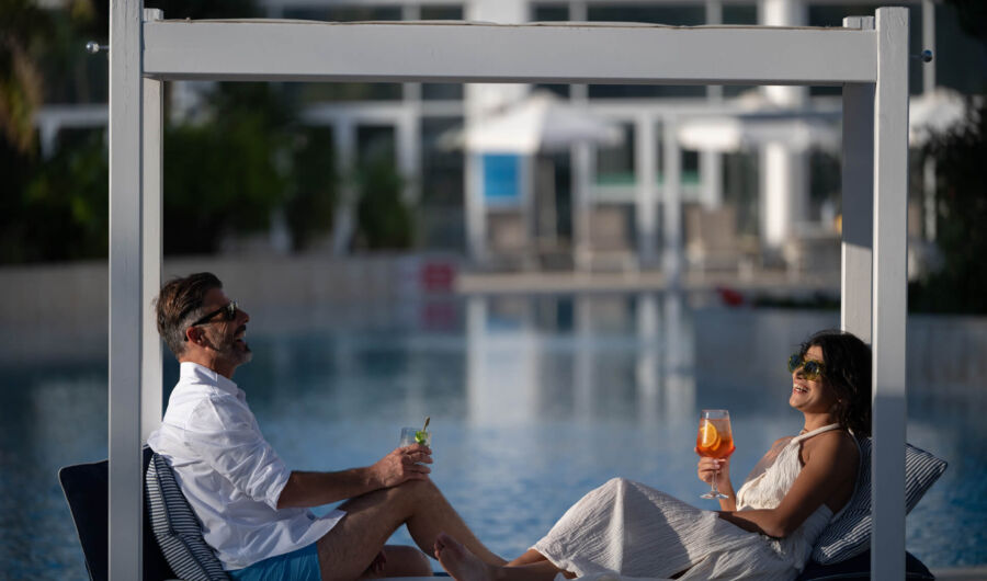 Couple laughing at a sunbed poolside