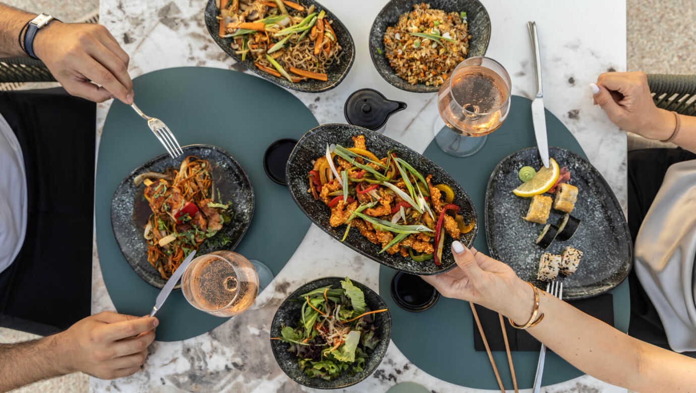 table of asian dishes and two people eating at Imperial Island resort