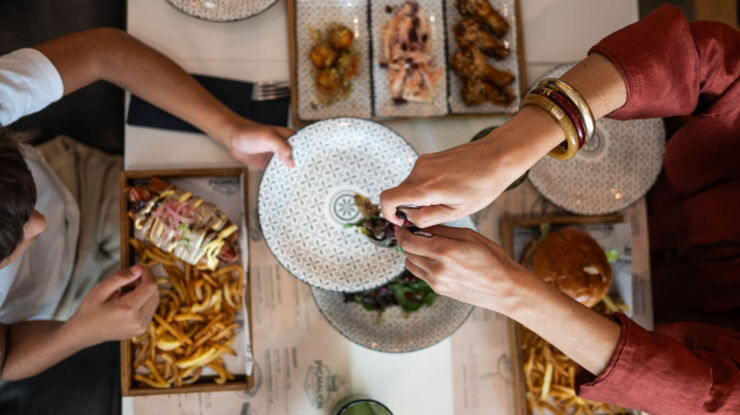 Man serving salad at woman while eating casual food at Imperial Island Resort