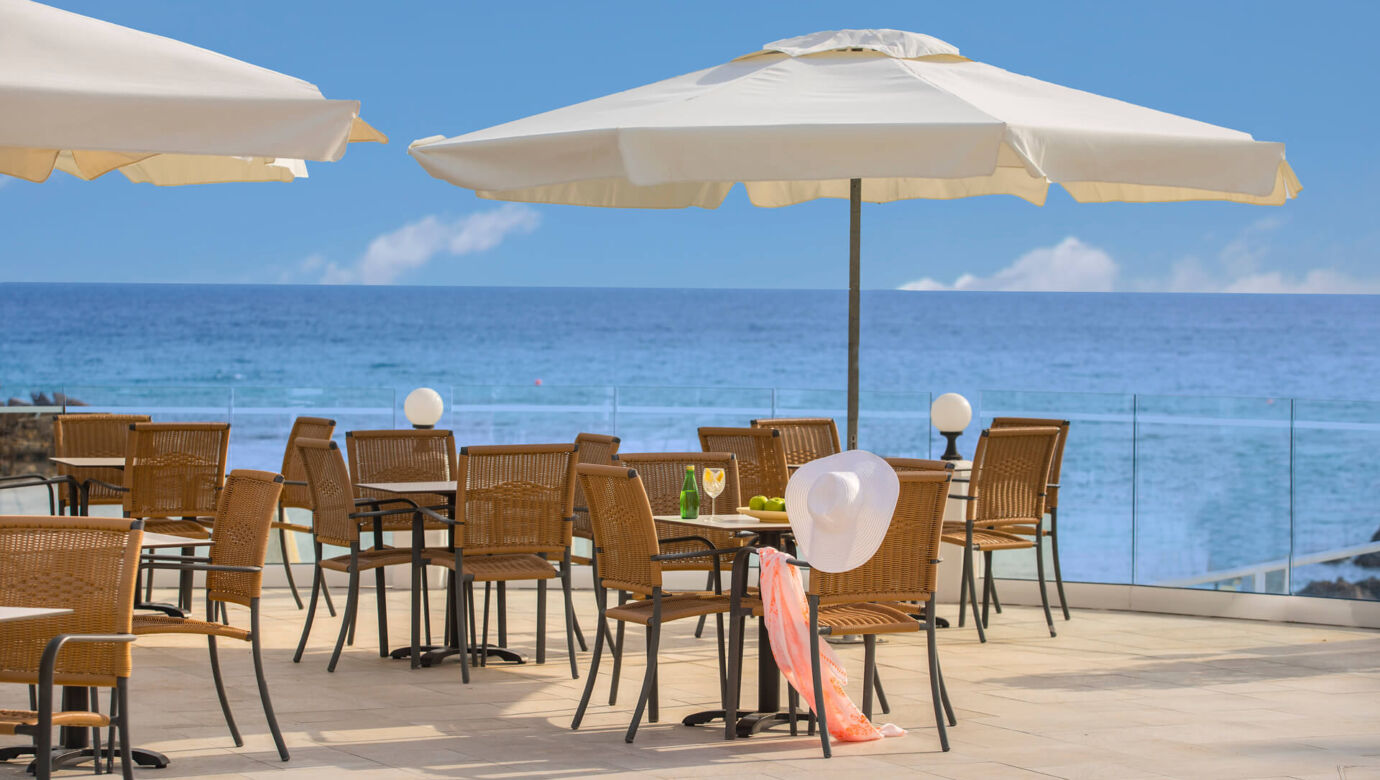 Tables with sea view at balcony with woman belongings hanging from chair