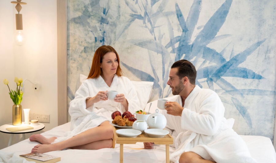 Couple eating breakfast in bed at Infinity Blu room