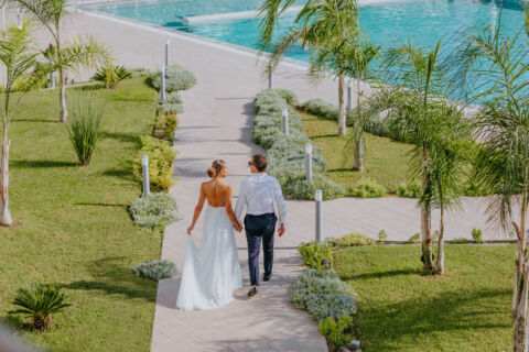 Newly married couple walking through garden at Ivi Mare