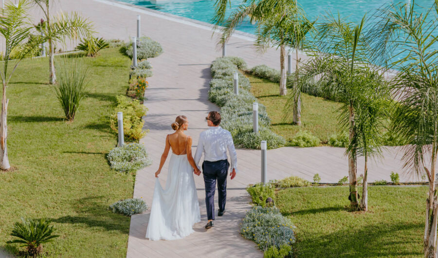 Newly married couple walking through garden at Ivi Mare
