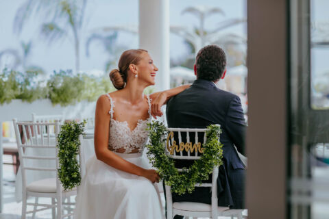 Newly married couple laughing and while sitting in decorated chairs