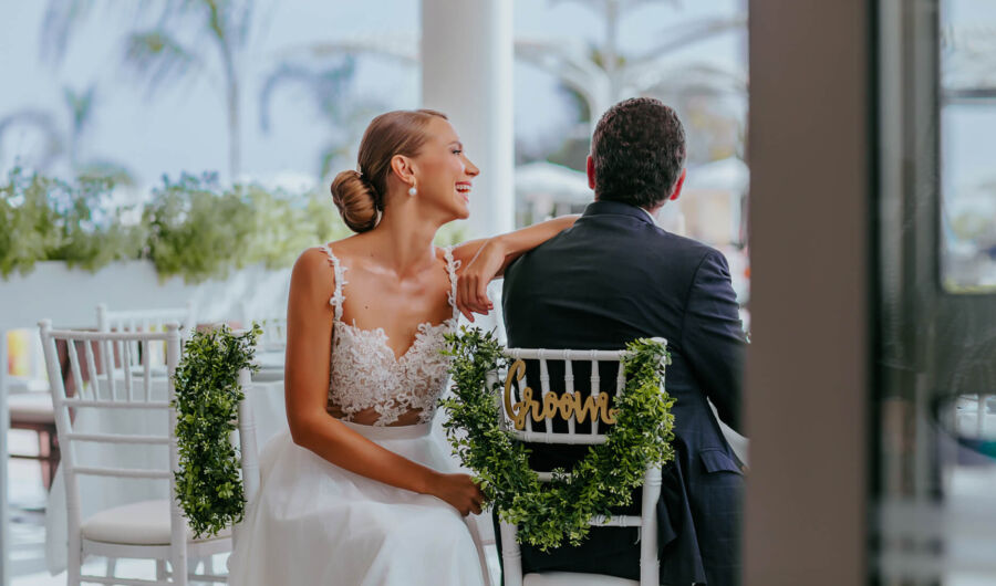 Newly married couple laughing and while sitting in decorated chairs