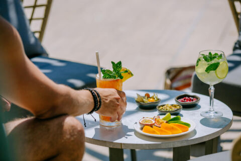 Man drinking cocktail and eating snacks