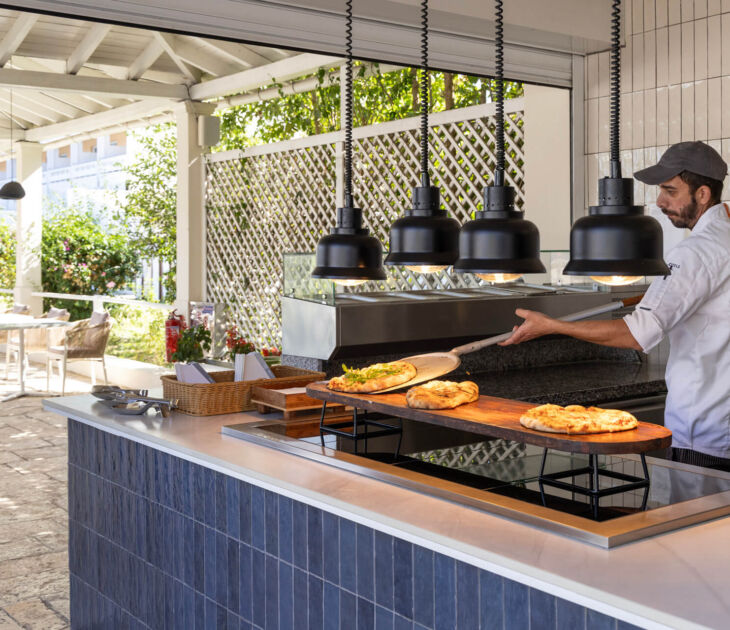Chef serving baked pizza at outdoor restaurant