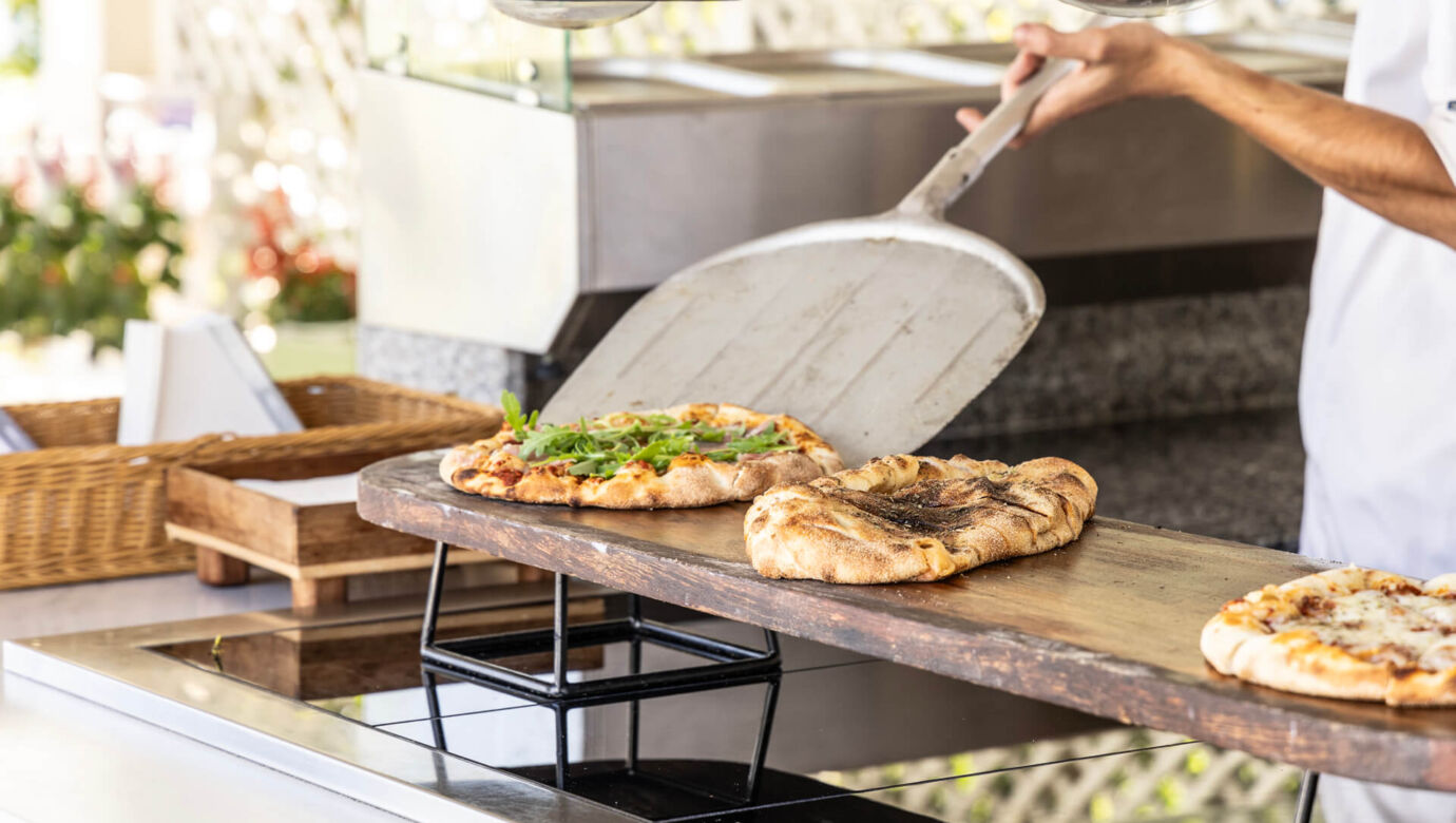 Chef serving fresh baked pizza at Kerkyra Blue restaurant