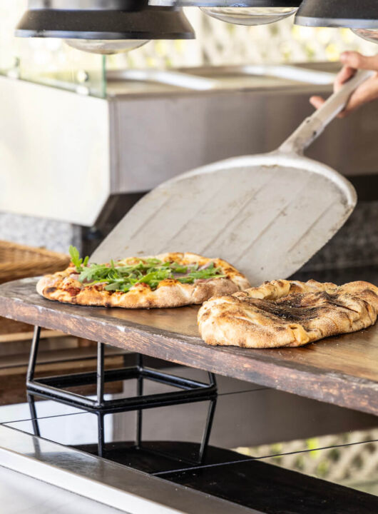 Chef serving fresh baked pizza at Kerkyra Blue restaurant