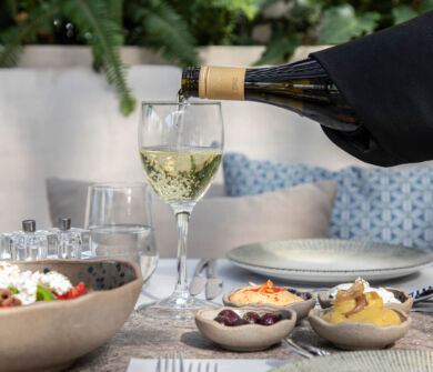 Waiter Serving wine into glass at a table with spreads and salada at Kerkyra Blue restaurant