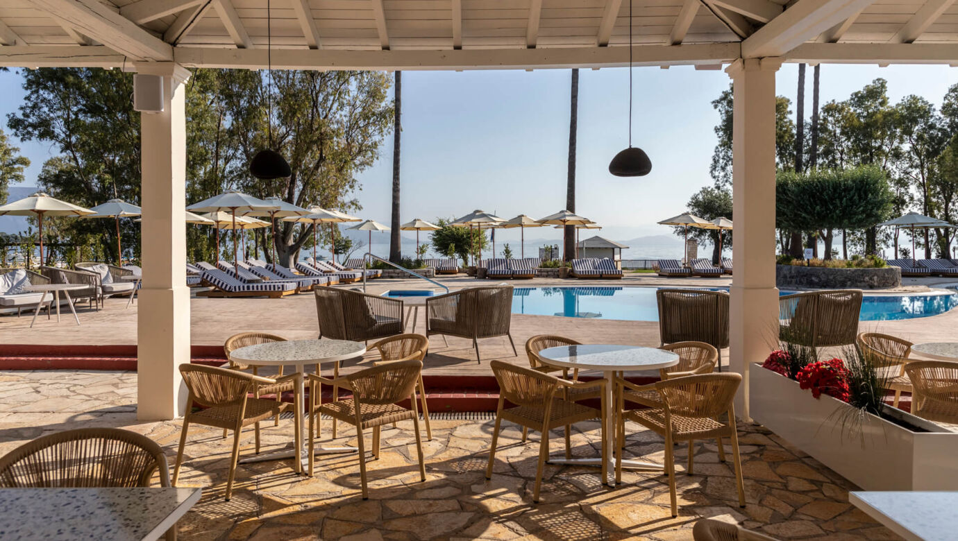 Outdoor tables near pool with sunbeds at Kerkyra Blue