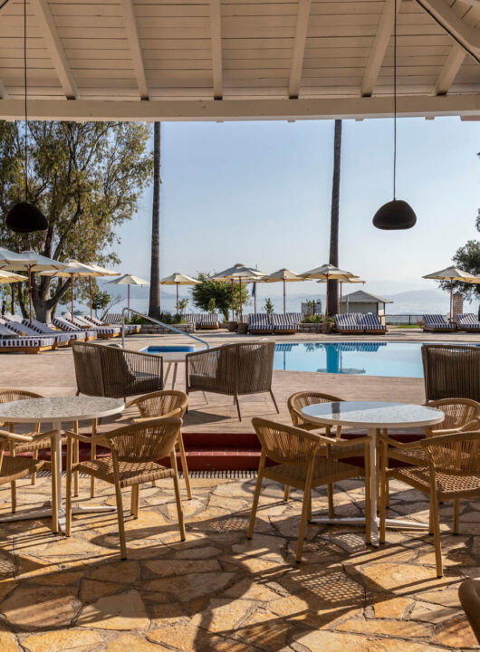 Outdoor tables near pool with sunbeds at Kerkyra Blue