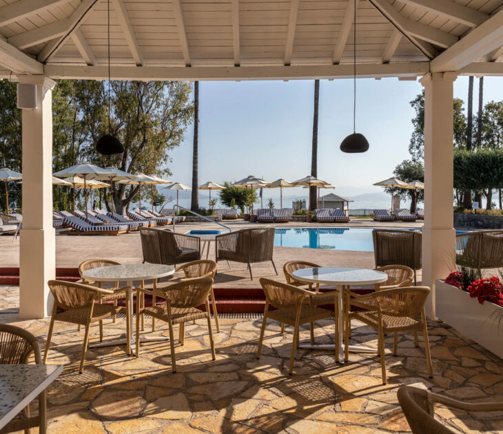 Outdoor tables near pool with sunbeds at Kerkyra Blue