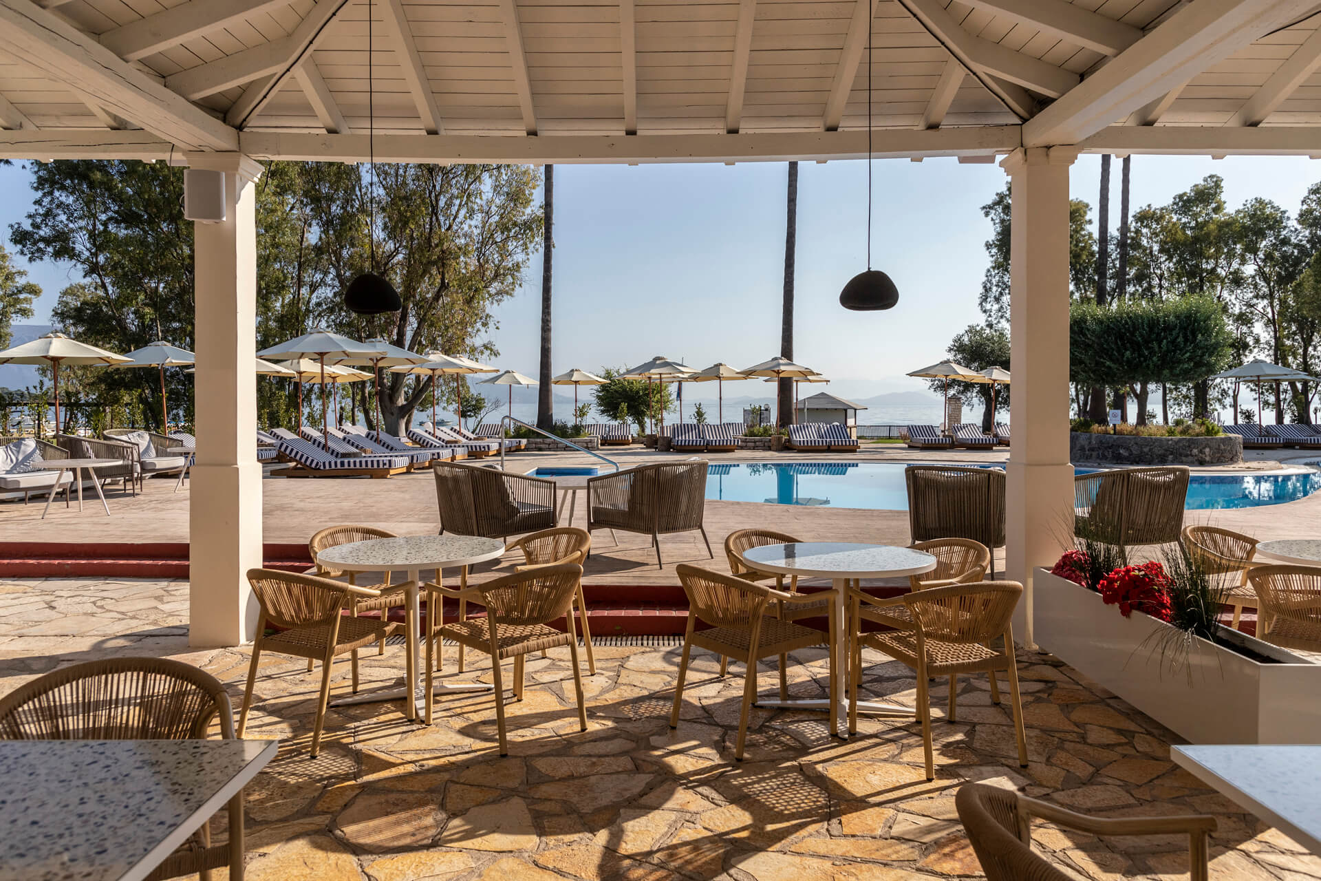 Outdoor tables near pool with sunbeds at Kerkyra Blue