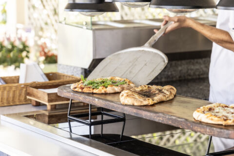 Chef serving freshly baked pizza at Kerkyra Blue