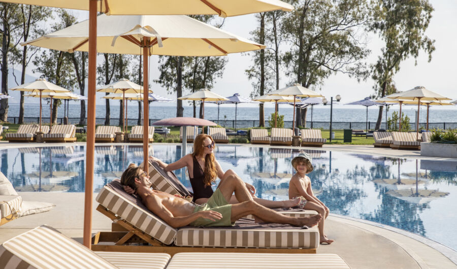 Family sitting at Kerkyra Blue pool and sunbeds