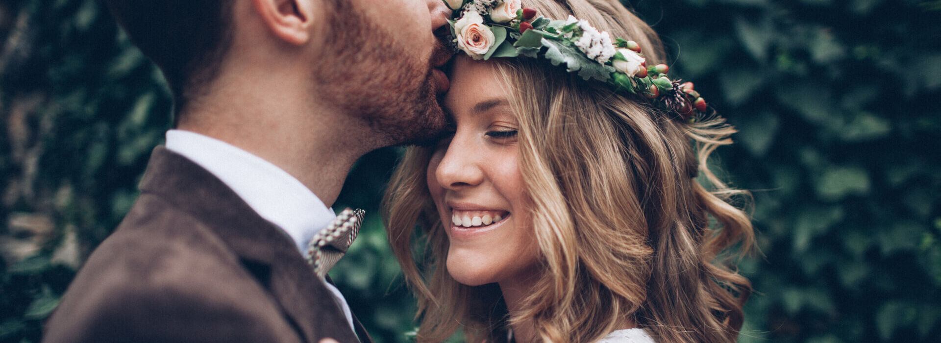 Man kissing bride on the forehead