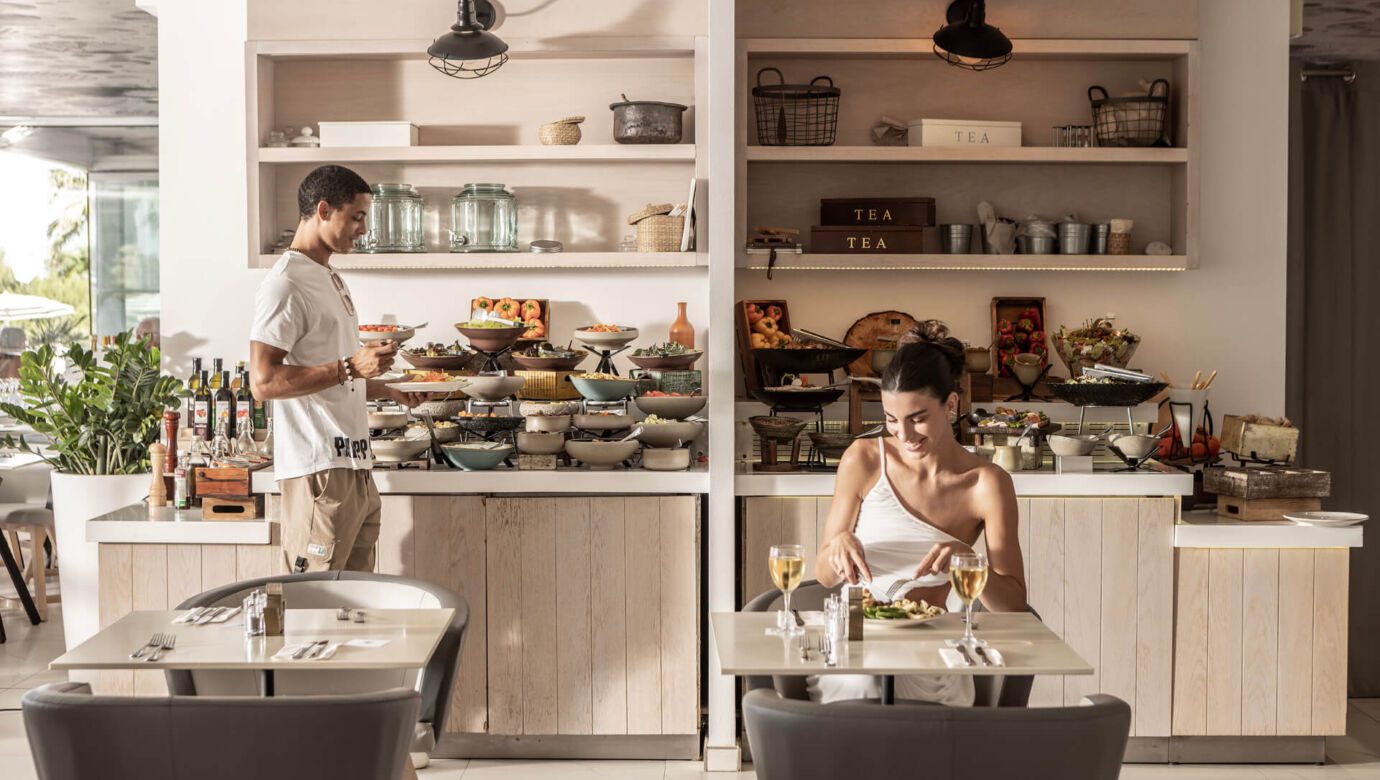 Woman eating and a man getting food from a buffet at King Jason Protaras
