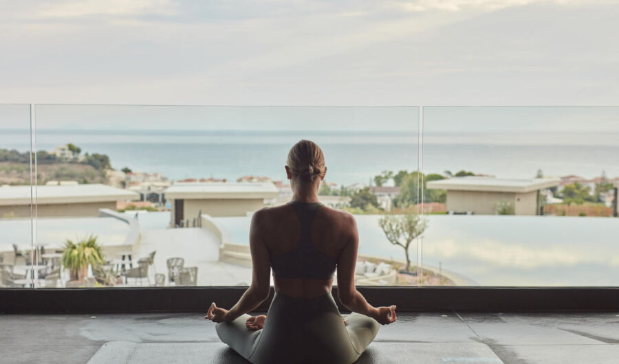 Woman doing yoga at King Jason Zante room balcony