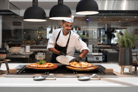 Chef serving freshly baked pizza at buffet