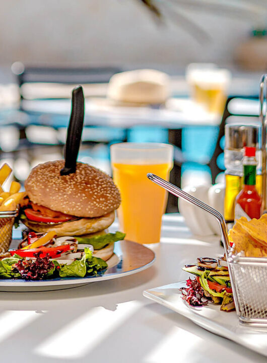 Table with burger and burrito poolside at Louis Althea restaurant