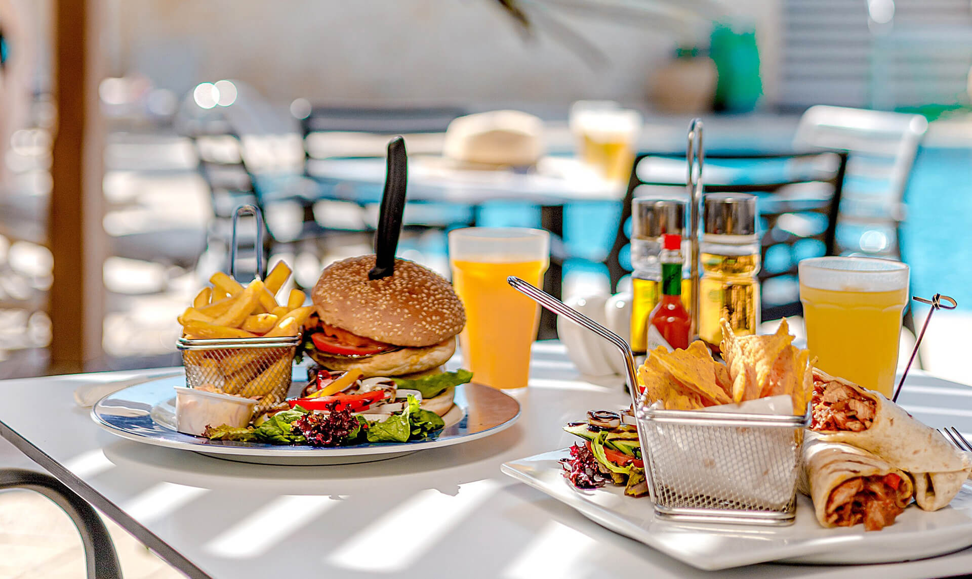 Table with burger and burrito poolside at Louis Althea restaurant