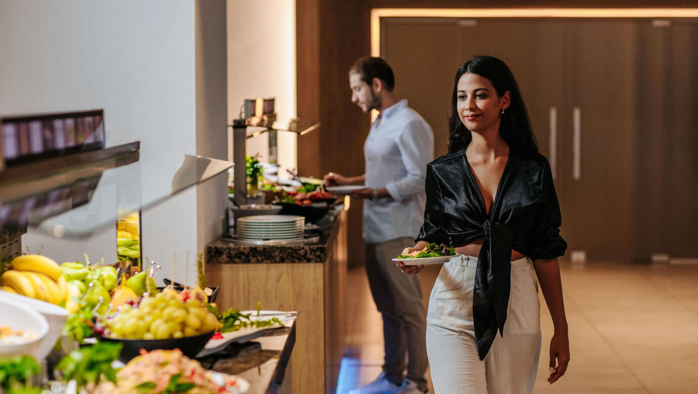 Woman getting food at Sofianna Resort restaurant buffet