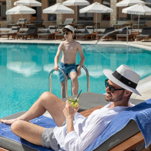 Father on subed and child at pool at Louis St. Elias Hotel