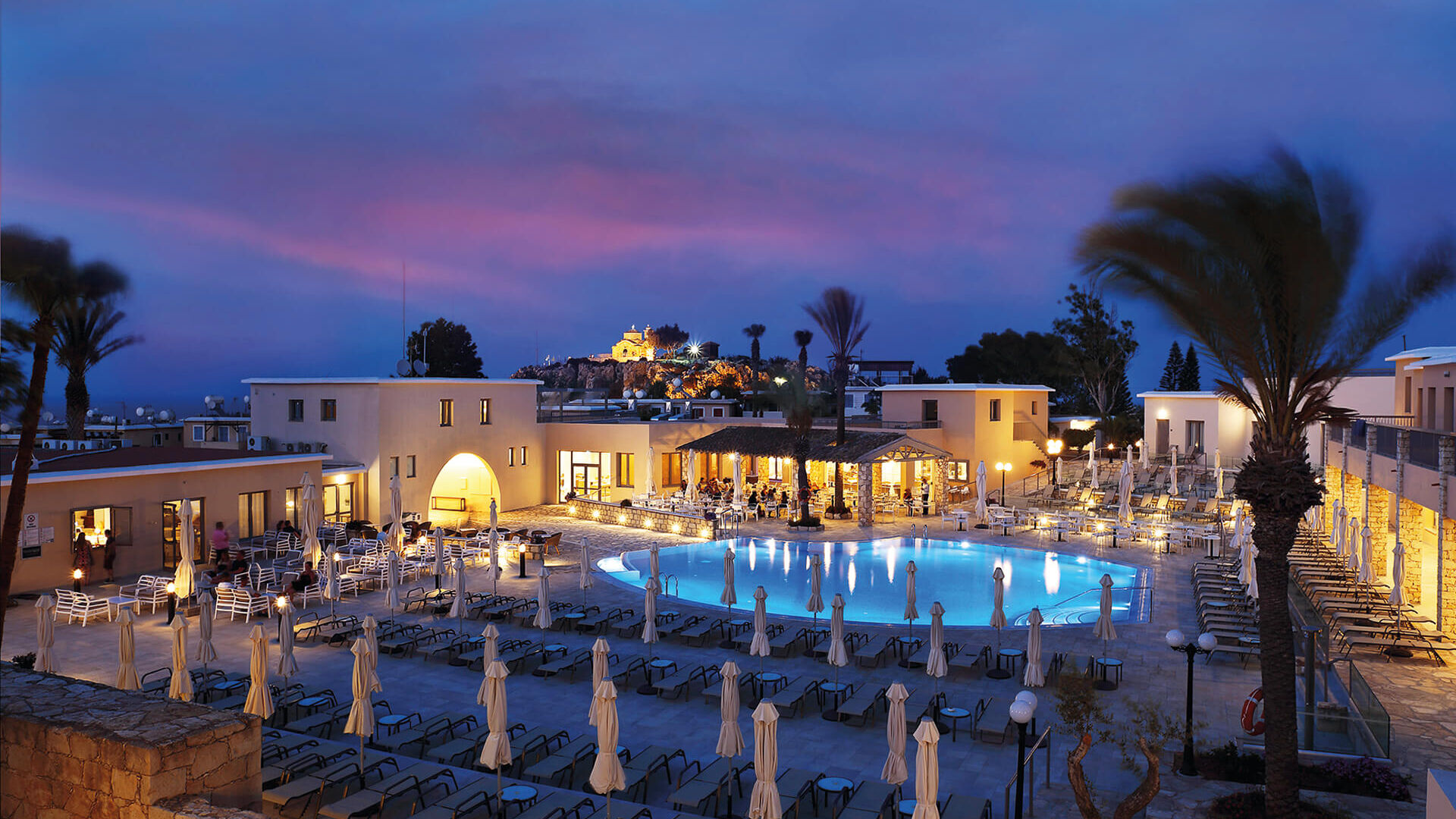Night view of the hotel pool and bar at Louis St. Elias