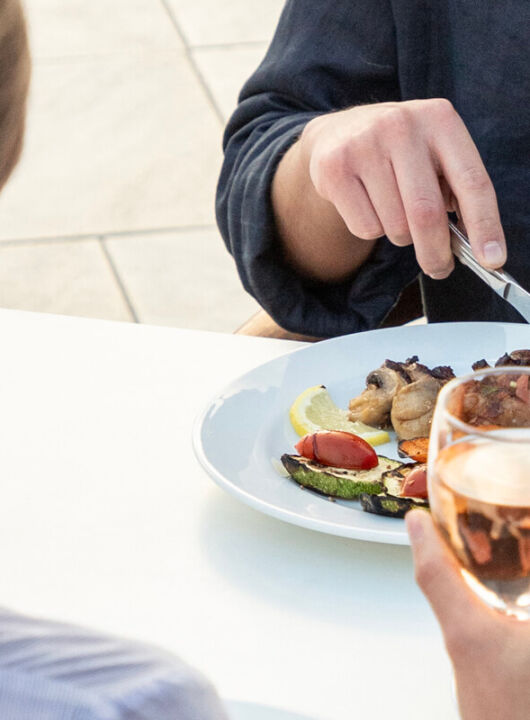 Woman holding wine and man eating at St. Elias Lemon tree restaurant