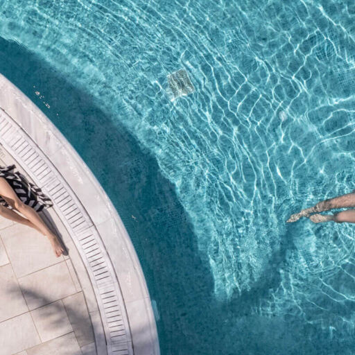 Woman Sunbathing and man swimming at Louis St. Elias pool