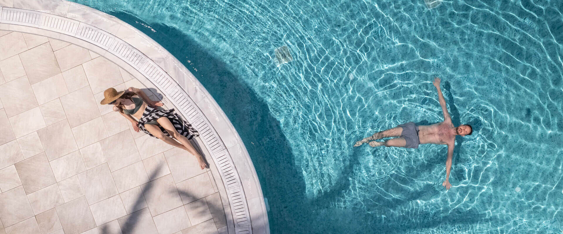 Woman Sunbathing and man swimming at Louis St. Elias pool