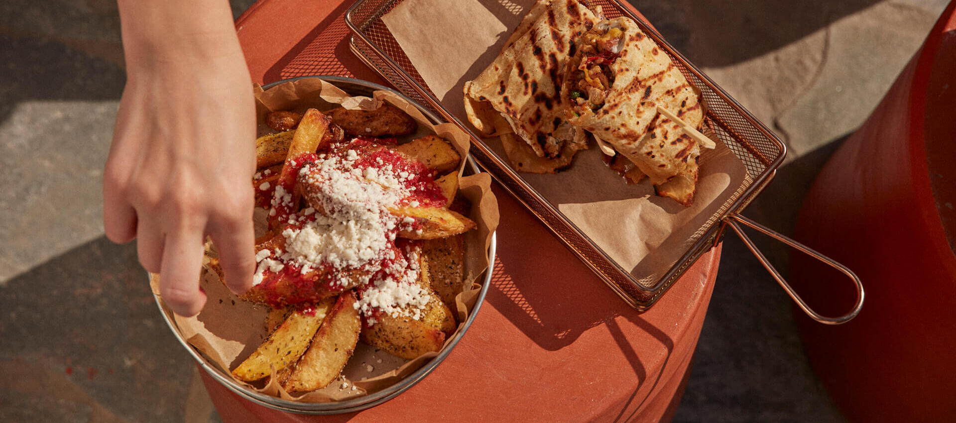 Table with two casual food dishes and a hand taking food
