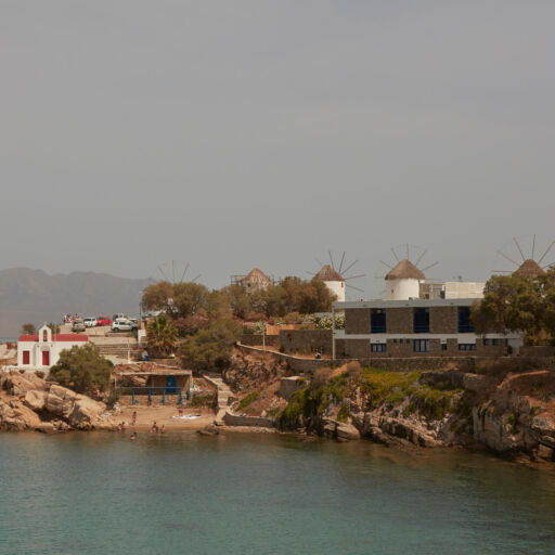 Rocky Beach with small church and people swimming