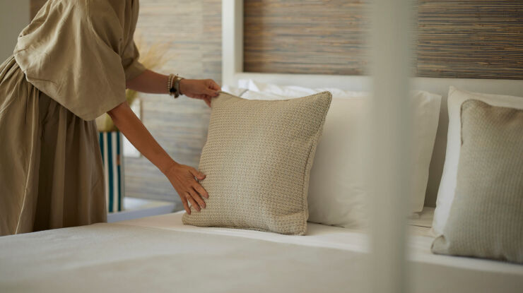 Woman preparing the bed in a room at Once In Mykonos