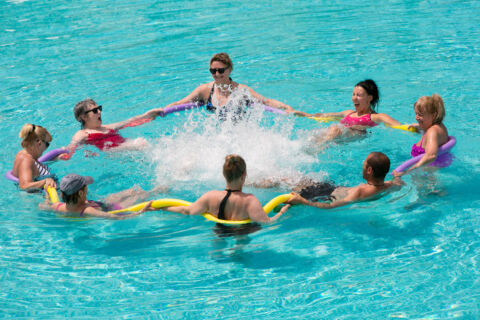 People with noodles pool swimming at the pool