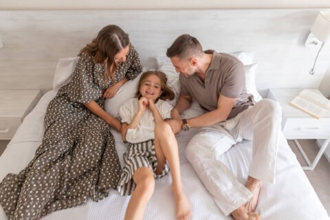 family playing and laughing on a bed