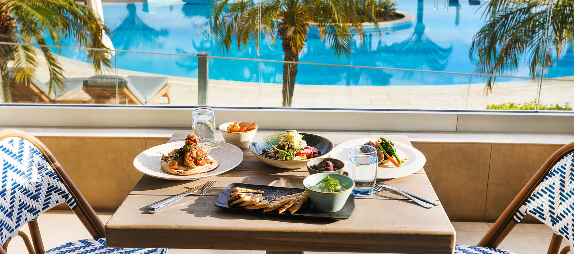 Table with food at Royal Apollonia Alati restaurant with pool view