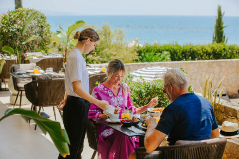 Couple eating breakfast while getting served coffee at Royal Apollonia Aura restaurant